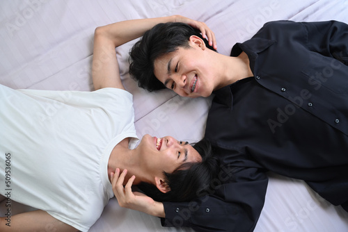 Overhead view young gay couple lying down on bed, spending time together. LGBT, pride, relationships and equality concept