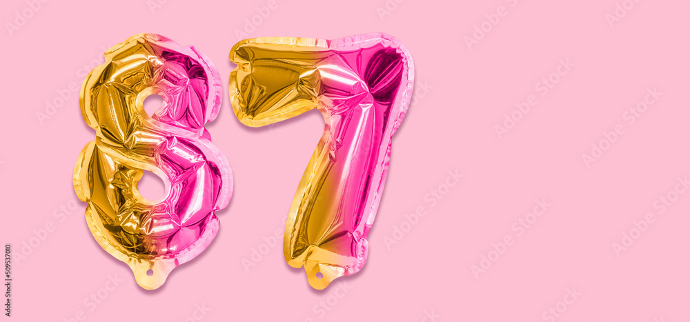 Rainbow foil balloon number, digit eighty seven on a pink background. Birthday greeting card with inscription 87. Top view. Numerical digit. Celebration event, template. Banner