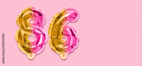 Rainbow foil balloon number, digit eighty six on a pink background. Birthday greeting card with inscription 86. Top view. Numerical digit. Celebration event, template. Banner