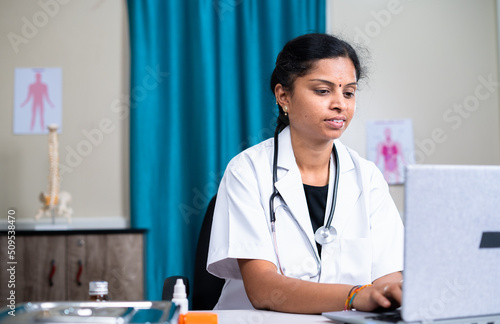 doctor at hopsital busy working on laptop for checking patient report - concept of professional occupation, healthcare and medical service or treatment photo