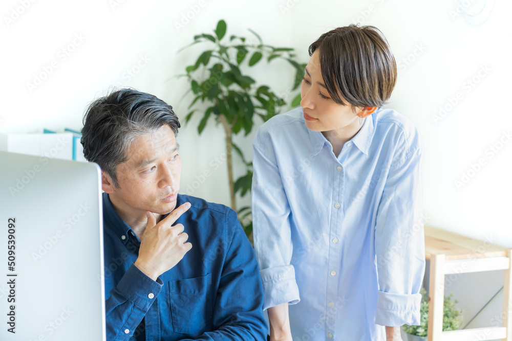 パソコンの前で話す二人の日本人男女 パソコンの前で話す二人の日本人男女