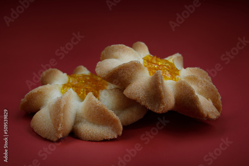 Two shortbread cookies on a red background . Kurabye cookies with jam . Beautiful cookies in the shape of a flower . photo