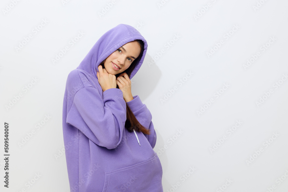 an interested woman stands on a white background in a purple tracksuit put a hood on her head and put her hands to her face a little embarrassed an interested woman stands on a white background in a purple tracksuit put a hood on her head and put her hands to her face a little embarrassed