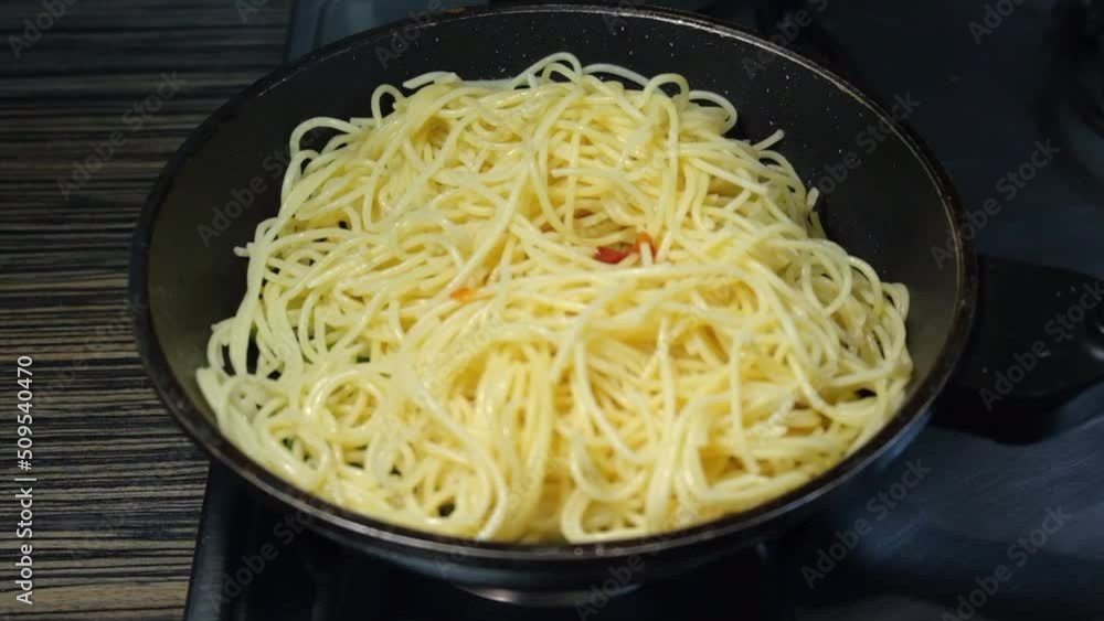 cooking and stirring the spaghetti with vegetable in the frying pan cooking and stirring the spaghetti with vegetable in the frying pan