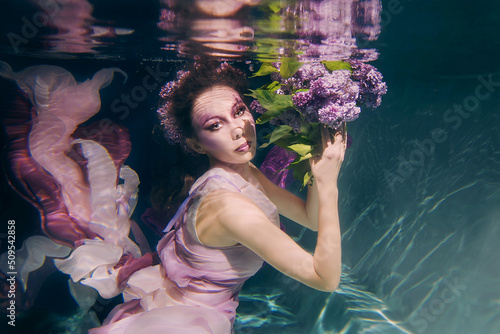 Tableau sur toile woman with lilac bouquet in colorful clothes on the dark background swimming und