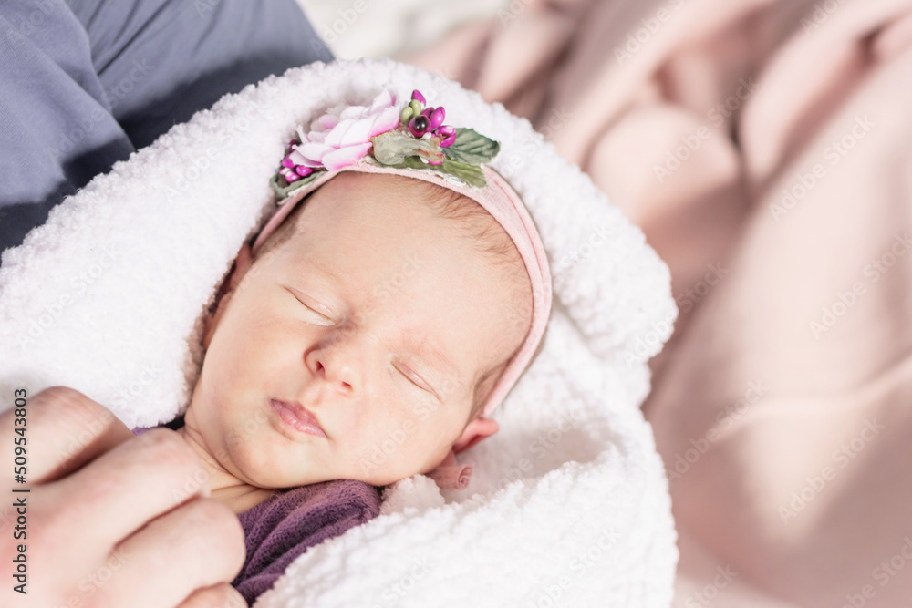 Sleeping newborn baby girl wrapped in a white fluffy blanket in the arms of the parents, first month Sleeping newborn baby girl wrapped in a white fluffy blanket in the arms of the parents, first month