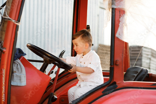 Little boy sitting in a tractor at sunset