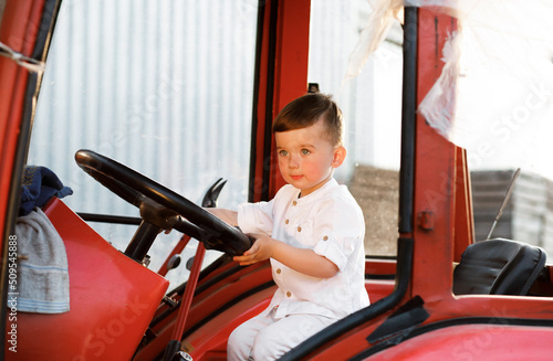 Little boy sitting in a tractor at sunset