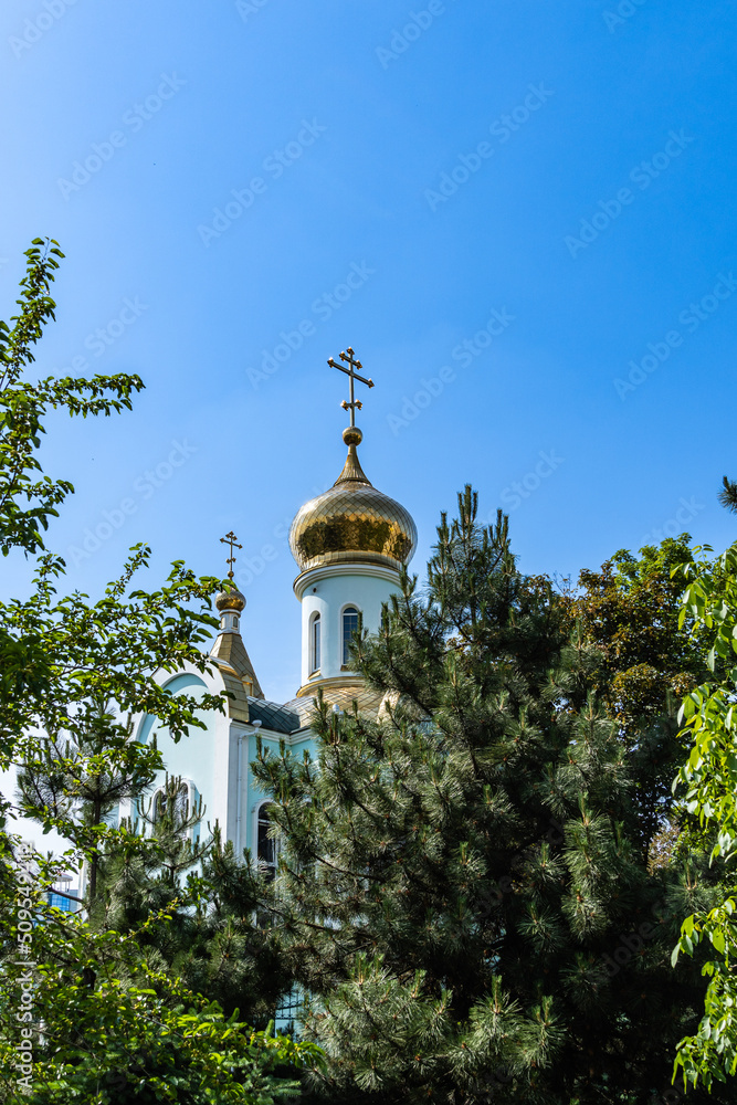 Temple of Kazan Icon of Mother of God. Golden domes with orthodox crosses against background of blue sky. Close-up. Russian Orthodox Church, Ekaterinodar diocese. Krasnodar, Russia - May 31, 2022