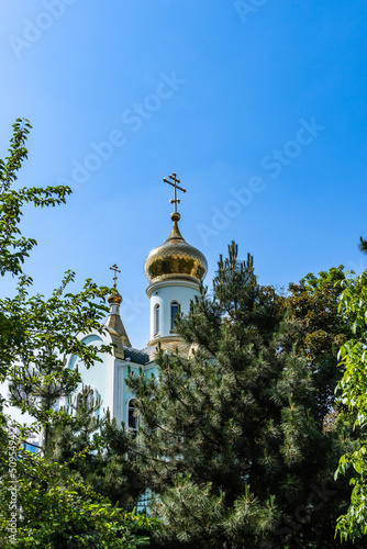 Temple of Kazan Icon of Mother of God. Golden domes with orthodox crosses against background of blue sky. Close-up. Russian Orthodox Church, Ekaterinodar diocese. Krasnodar, Russia - May 31, 2022