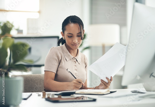 Filing her annual taxes. Shot of a young businesswoman calculating finances in an office.