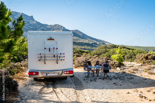 Foto Family traveling with motorhome are eating breakfast on a beach.