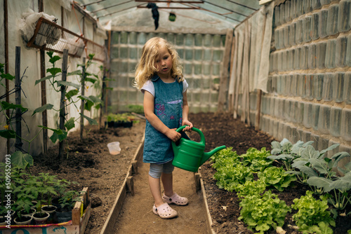 Little blonde girl gardening in the greenhouse