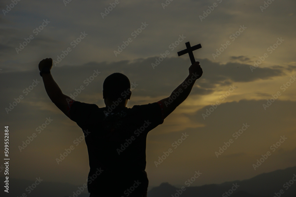 Shadow of a man holding a cross in the evening sunlight