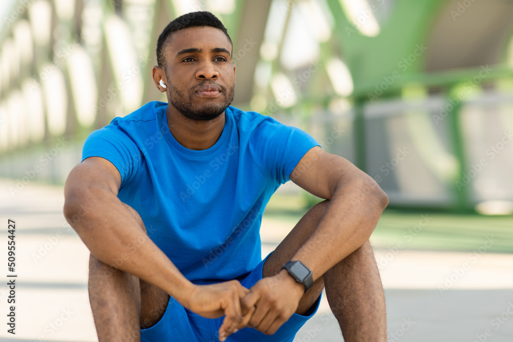 Fototapeta premium Fitness and healthy lifestyle concept. Athletic young guy sitting on the floor after training