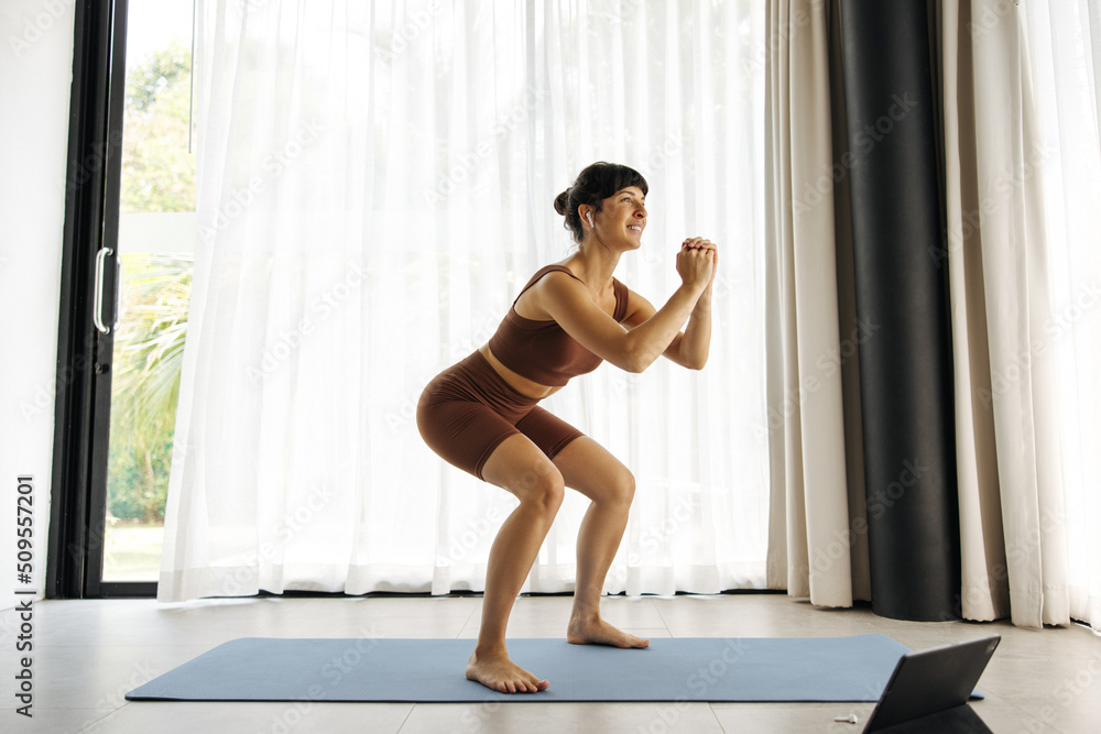 Beautiful young caucasian girl does exercises on muscles of buttocks on mat indoors. Brunette wears brown top and leggings in training. Keep yourself in shape concept. Beautiful young caucasian girl does exercises on muscles of buttocks on mat indoors. Brunette wears brown top and leggings in training. Keep yourself in shape concept.
