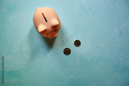 różowa świnka skarbonka i monety na niebieskim tle 