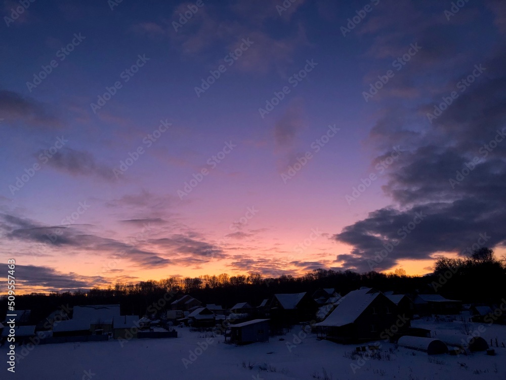 Small village in winter against the background of a fabulous sunset.