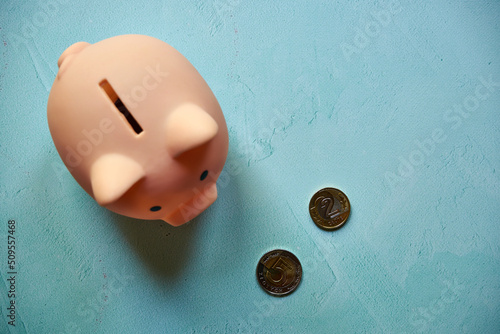 różowa świnka skarbonka i monety na niebieskim tle  photo