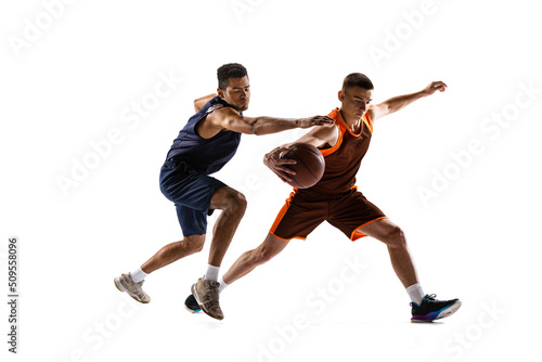 Portrait of two sportive men, basketball players in uniform playing, training isolated over white studio background