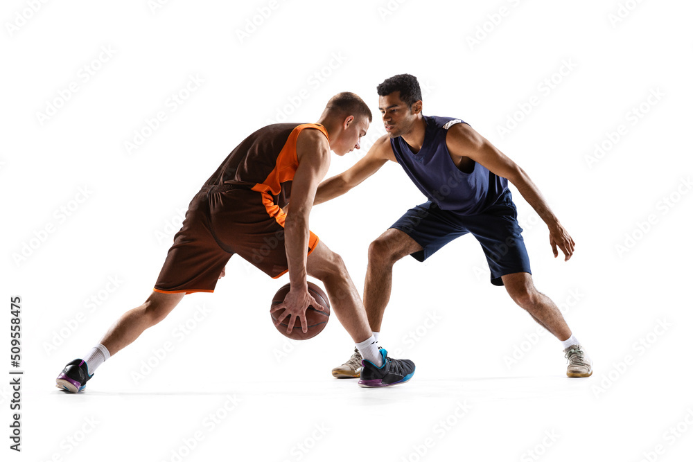 Dynamic portrait of two professional basketball players in motion, training isolated over white studio background. Two hands dribbling