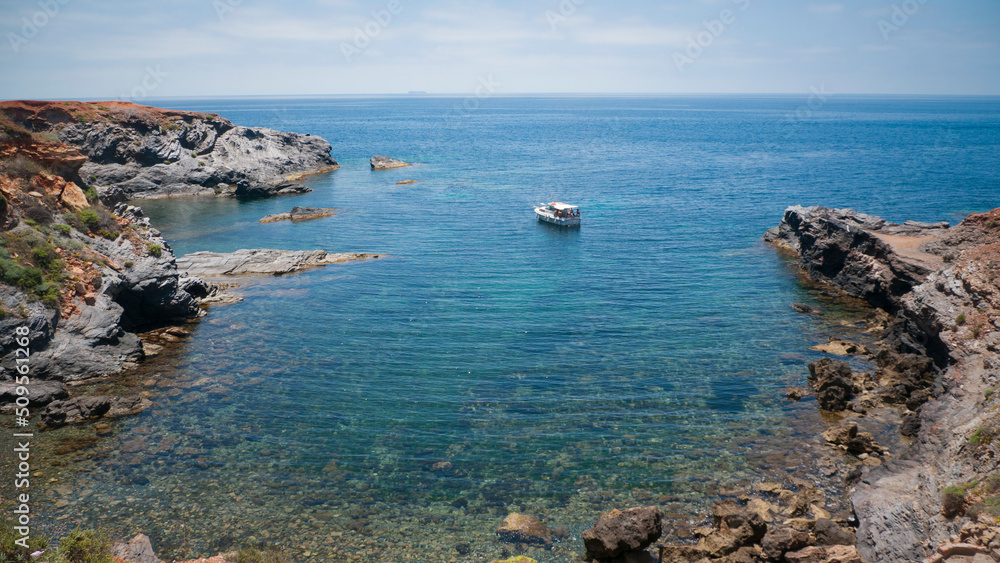 Pequeña embarcación de recreo fondeando en cala del litoral mediterráneo