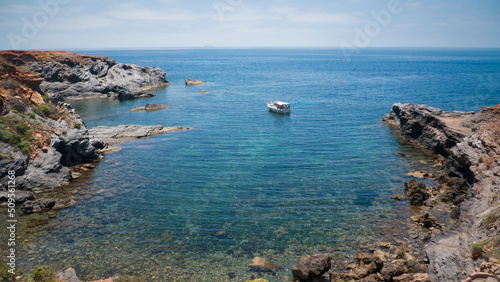 Pequeña embarcación de recreo fondeando en cala del litoral mediterráneo photo