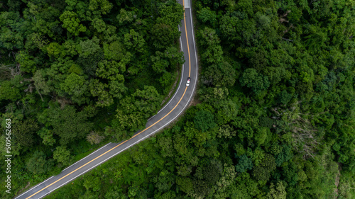 Aerial top view of the the road, Aerial view tropical rain forest with asphalt road cutting through, Road through the green forest Ecosystem and healthy environment background.