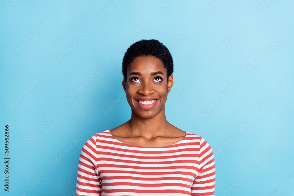 Photo of cheerful lovely lady look up empty space shiny smile wear striped shirt isolated blue color background Photo of cheerful lovely lady look up empty space shiny smile wear striped shirt isolated blue color background
