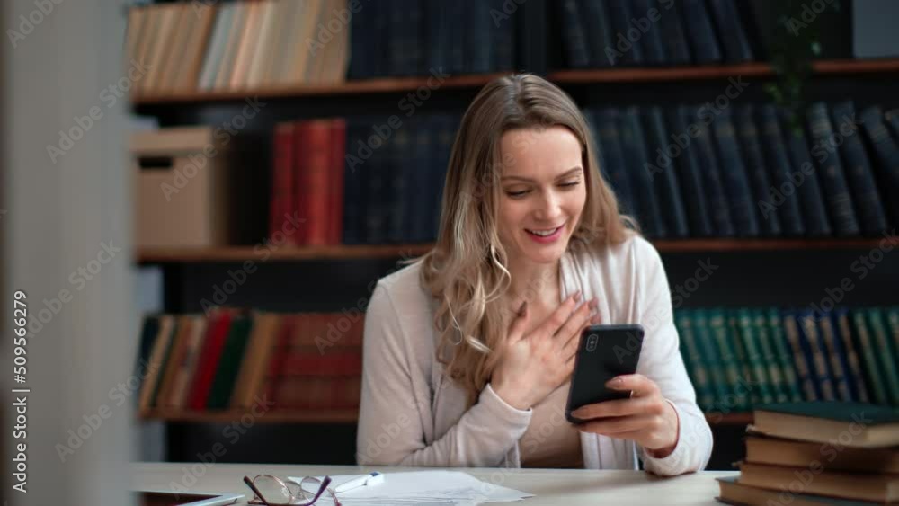 Overjoyed professor student teacher business woman received good news smartphone message at library Overjoyed professor student teacher business woman received good news smartphone message at library