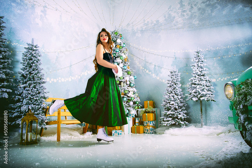 a charming girl is happy about the new year and poses on the ice rink dressing up a Christmas tree photo