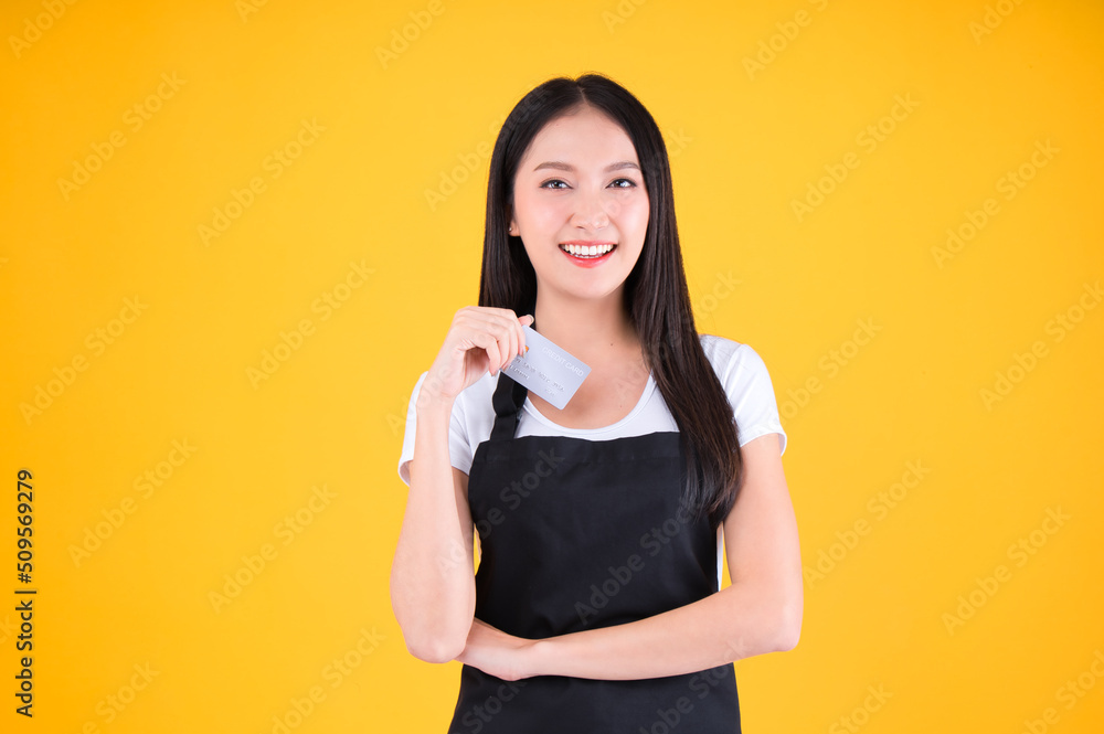 entrepreneur pretty asian female smile wearing black apron pointing fingers to credit card. entrepreneur pretty asian female smile wearing black apron pointing fingers to credit card.