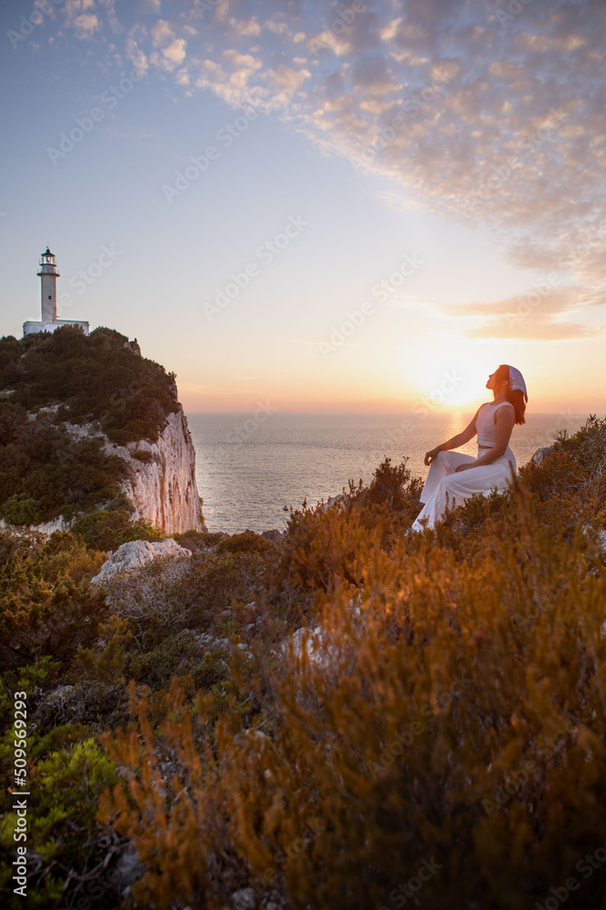 happy woman sitting at the cliff view view of Lefkada island lighthouse