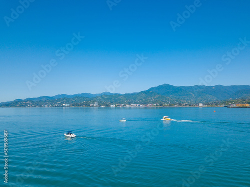 Drone view of motorboats at sea against the background of mountains on a sunny clear day