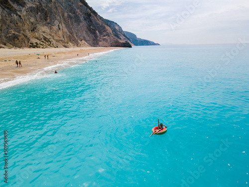 aerial view of greece beach woman floating on inflatable ring