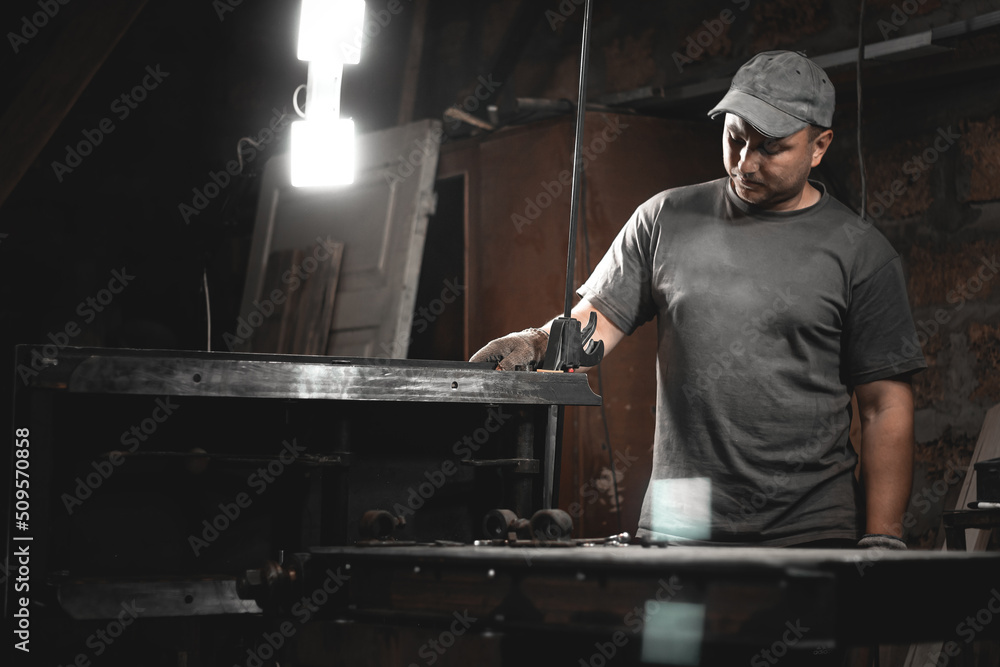 A worker prepares a woodworking machine for work in his home workshop. Making metal products with your own hands A worker prepares a woodworking machine for work in his home workshop. Making metal products with your own hands