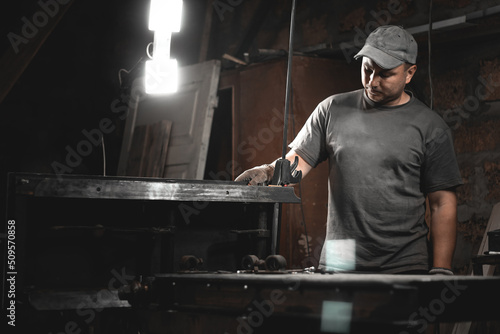 A worker prepares a woodworking machine for work in his home workshop. Making metal products with your own hands