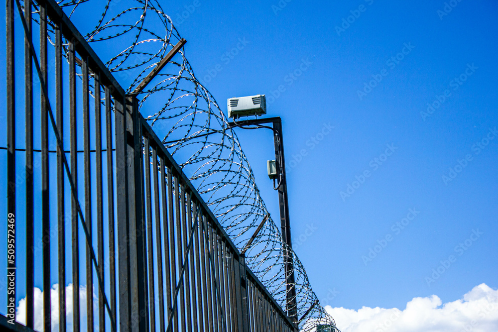 Fototapeta premium Barbed wire on a high fence against the sky. Barbed wire on the border of the country. Security of the border area.