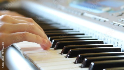A woman's hand presses the keys of a synthesizer, playing a slow melody on the piano, playing a synthesizer