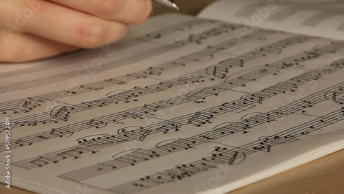 Handwritten notes and female hand holding a pen and writing notes, composing music, selective focus