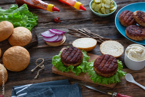  process of cooking delicious burgers with grilled meat cutlets, various sauces and vegetables