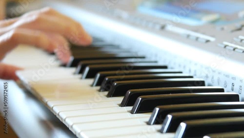 A woman's hand presses the keys of a synthesizer, playing a slow melody on the piano, playing a synthesizer