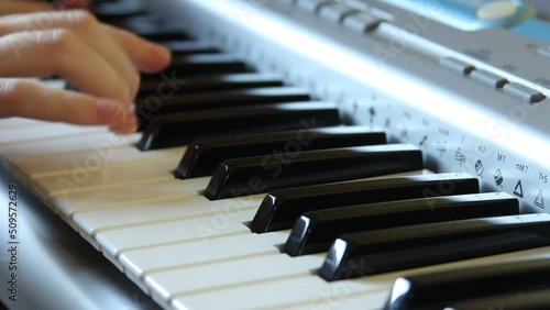 A woman's hand presses the keys of a synthesizer, playing a slow melody on the piano, playing a synthesizer