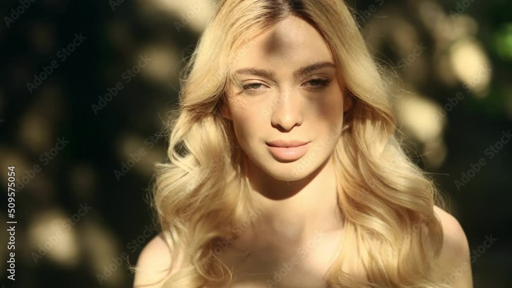 Close up of young stunning blond woman standing on the sun rays and looking at the camera. Gorgeous woman outside. Close up of young stunning blond woman standing on the sun rays and looking at the camera. Gorgeous woman outside.
