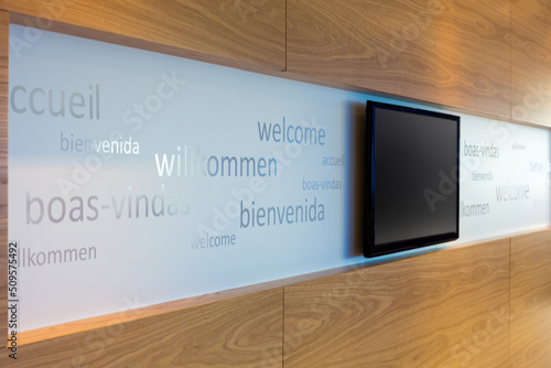 A welcoming office foyer with signage in multiple languages with flat screen TV photo