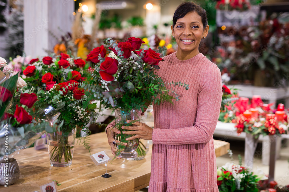 American female shopper holding composition from natural flowers at flower shop