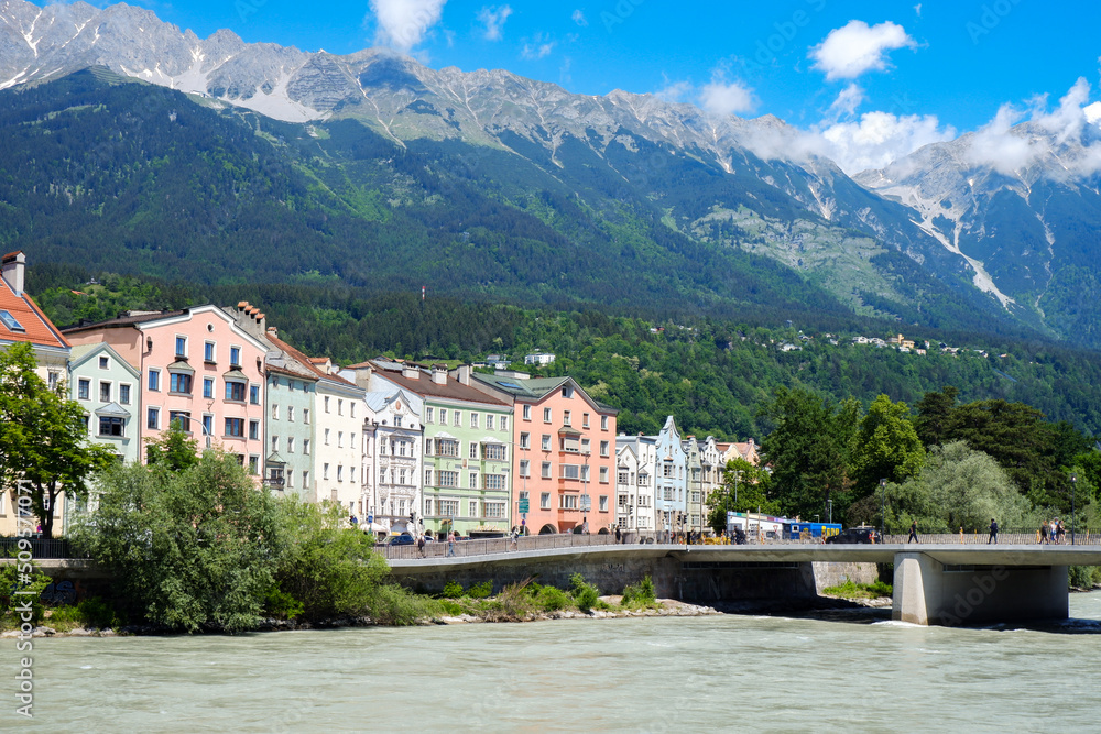 INNSBRUCK, AUSTRIA - May 26, 2022: Colourful Houses Innsbruck on Mariahilf Street along the Inn River with view of Alps in the summer