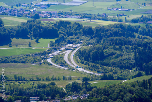 Aerial view of midland with agricultural fields, wood, hills and highway with tunnel portal seen from local mountain Uetliberg on a sunny spring day. Photo taken May 18th, 2022, Zurich, Switzerland.