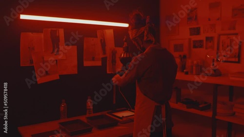 Rear view of male photographer working with film and photos in darkroom photo