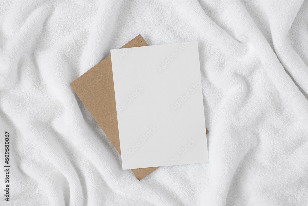 Blank paper on white terry towel with copy space. Paper mockup for postcard or advertisement. Blank paper on white terry towel with copy space. Paper mockup for postcard or advertisement.